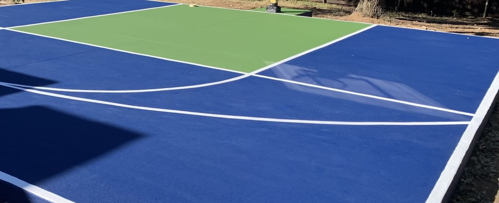 Freshly coated blue court with a green key and crisp white basketball lines